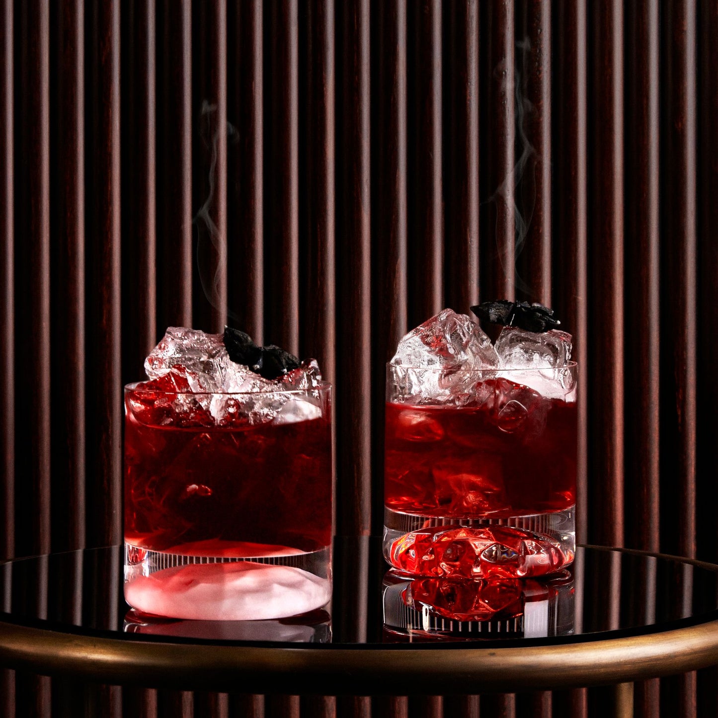Four minimalist crystal whisky tumblers arranged elegantly in a contemporary home bar setting.