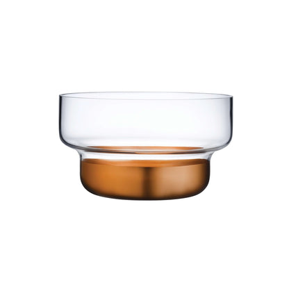 Minimalist clear glass bowl resting on a warm metallic copper base, showcasing modern tabletop design.
