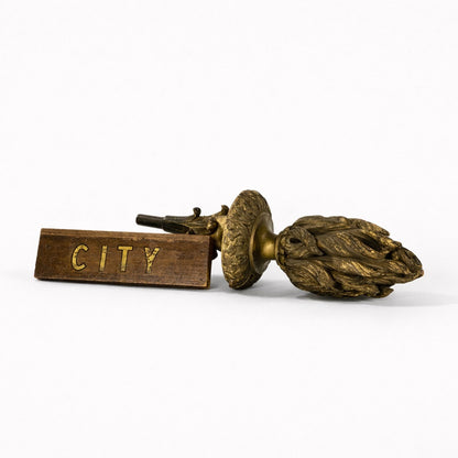 Bronze and wooden object with 'CITY' engraving on a white background