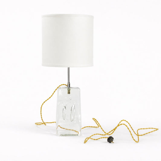 Table lamp with a white shade and clear rectangular base on a white background