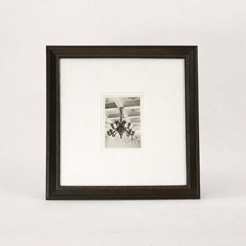 Framed black and white photo of a chandelier on a white background