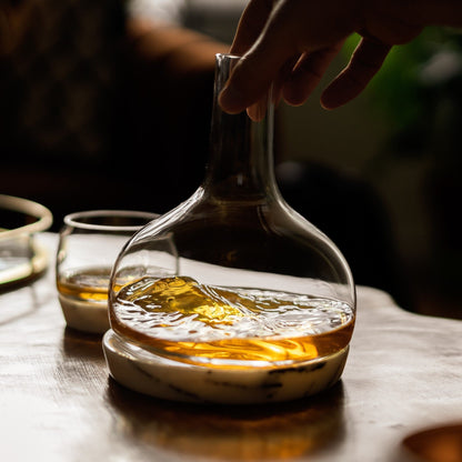 Detailed view of liquid swirling inside the clear crystal carafe on its marble base.