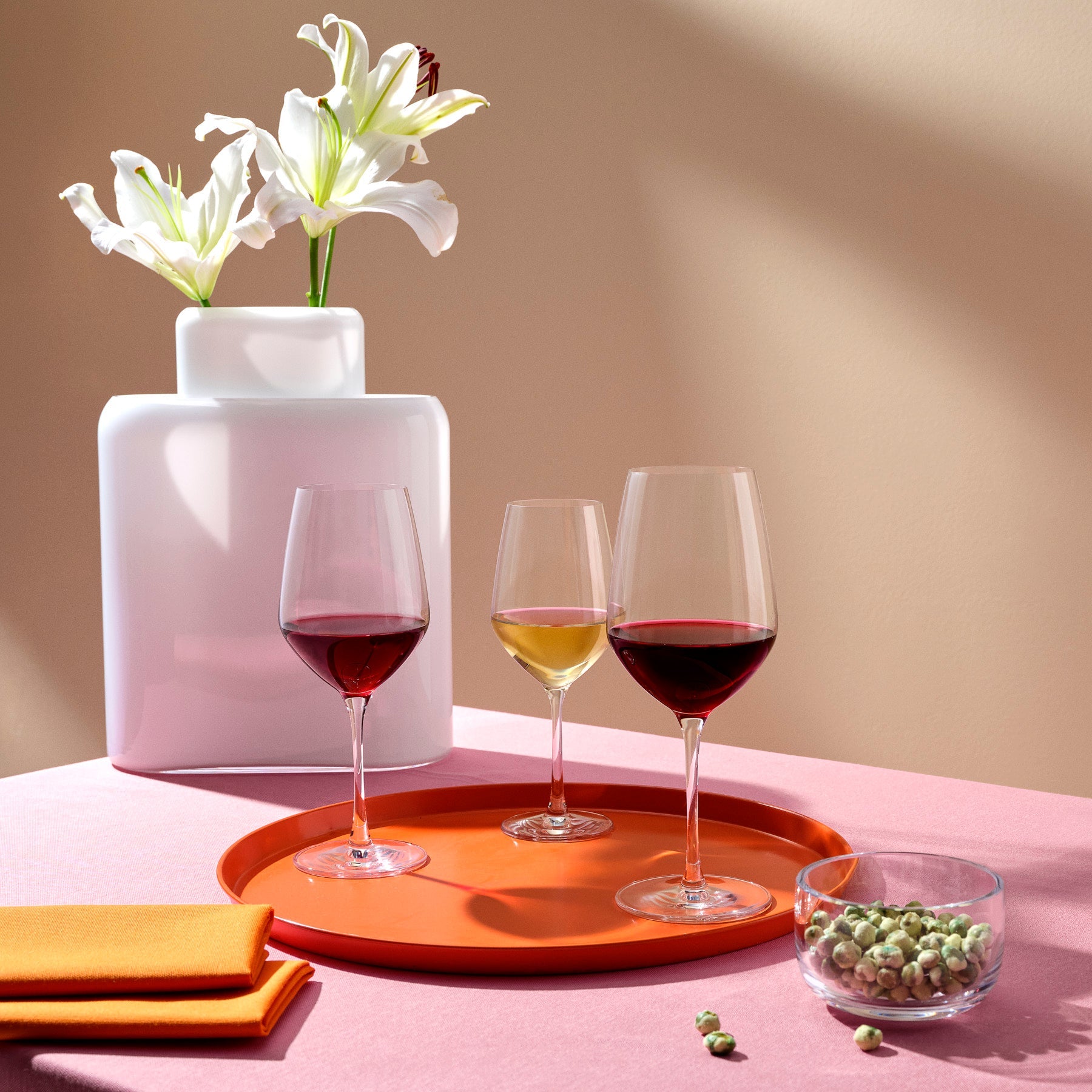 An elegant table setting featuring the Climats glassware collection, including red wine glasses and decorative crystal vases.