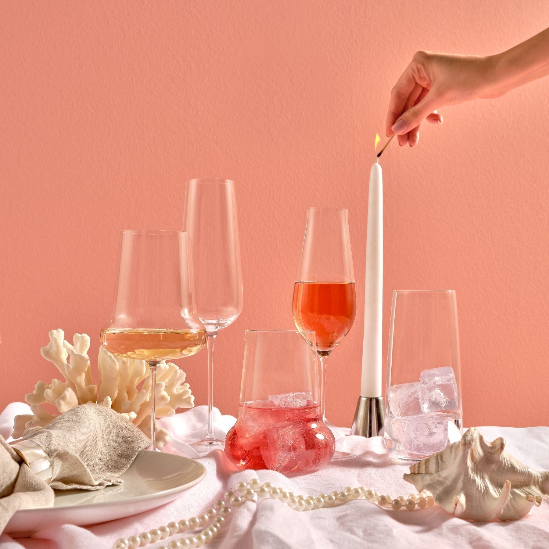 An elegant curation of NUDE Glass modern crystal stemware and highball glasses on a minimalist tabletop.