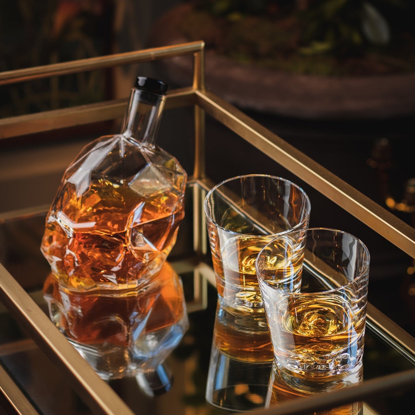 The Memento Mori whiskey decanter displayed on a styled wooden shelf alongside luxury barware accessories.