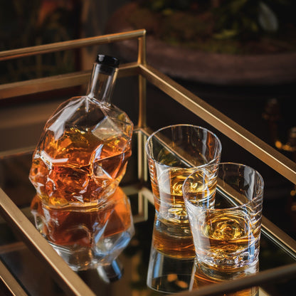 The Memento Mori whiskey decanter displayed on a styled wooden shelf alongside luxury barware accessories.
