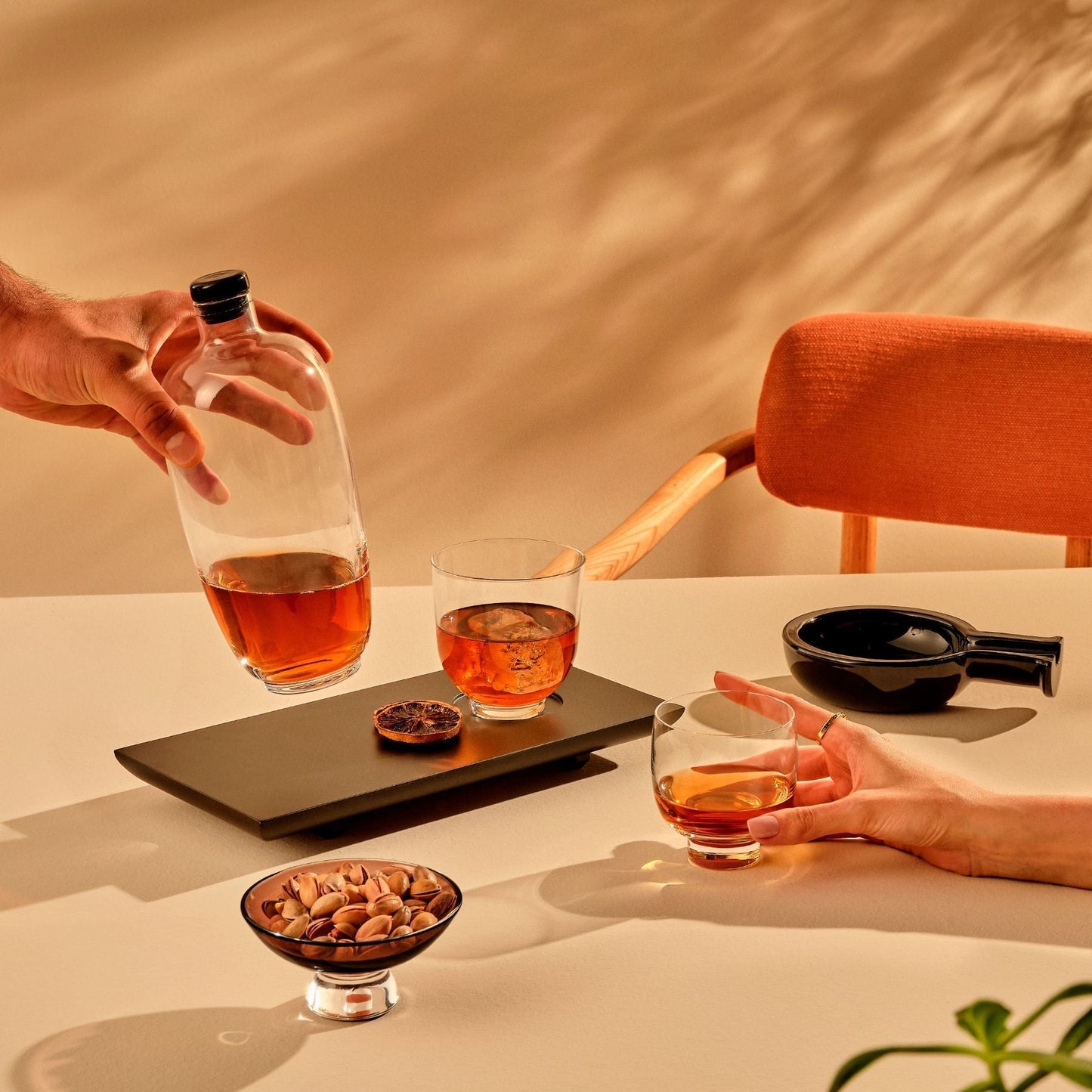 Luxury barware display featuring the NUDE Egoist cigar ashtray alongside a malt whisky bottle, tray, and lowball glass.