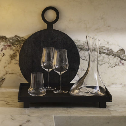A clean, minimalist kitchen shelf displaying a selection of NUDE crystal glassware.