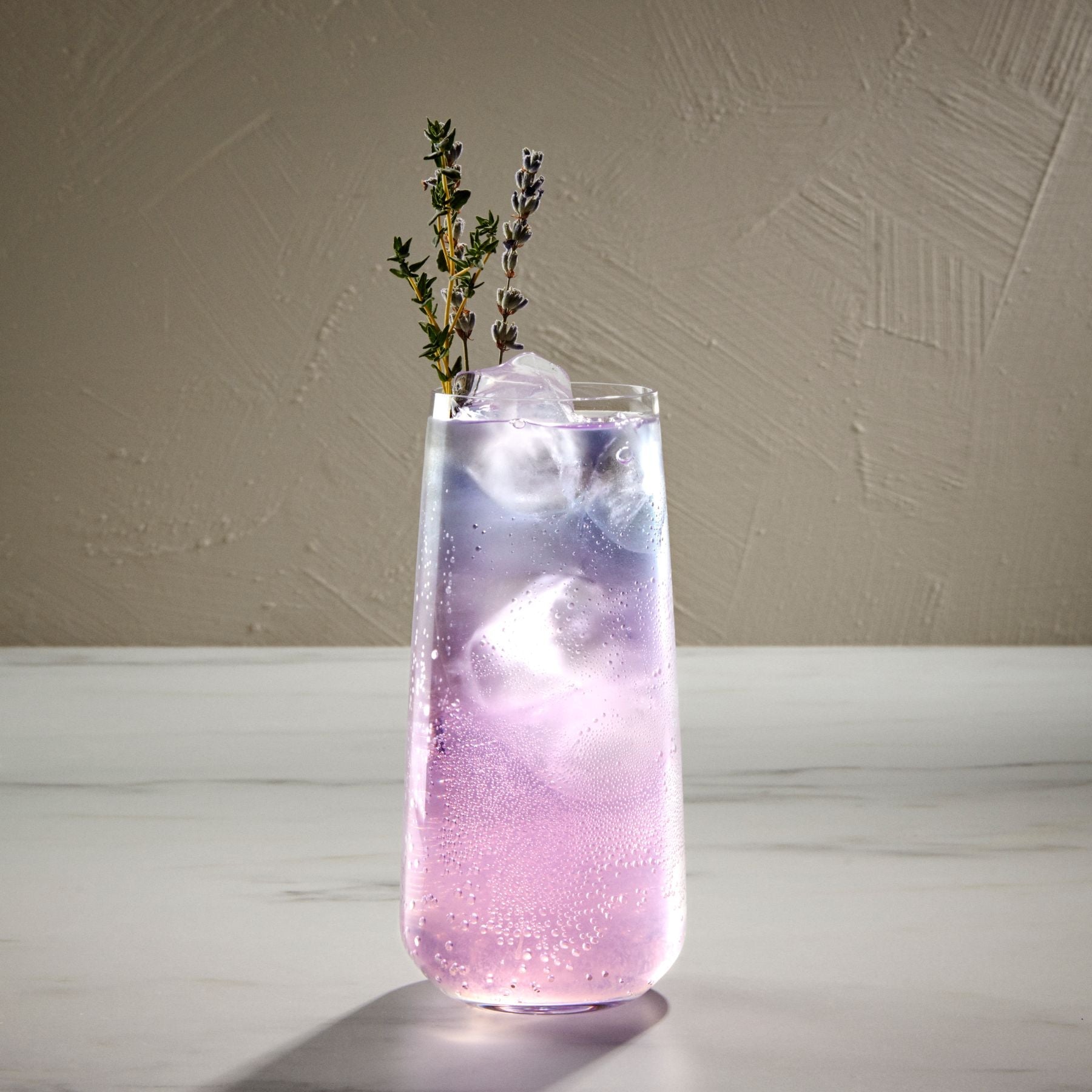 A modern lifestyle setting with Mirage long drink glasses arranged on a minimalist stone countertop.