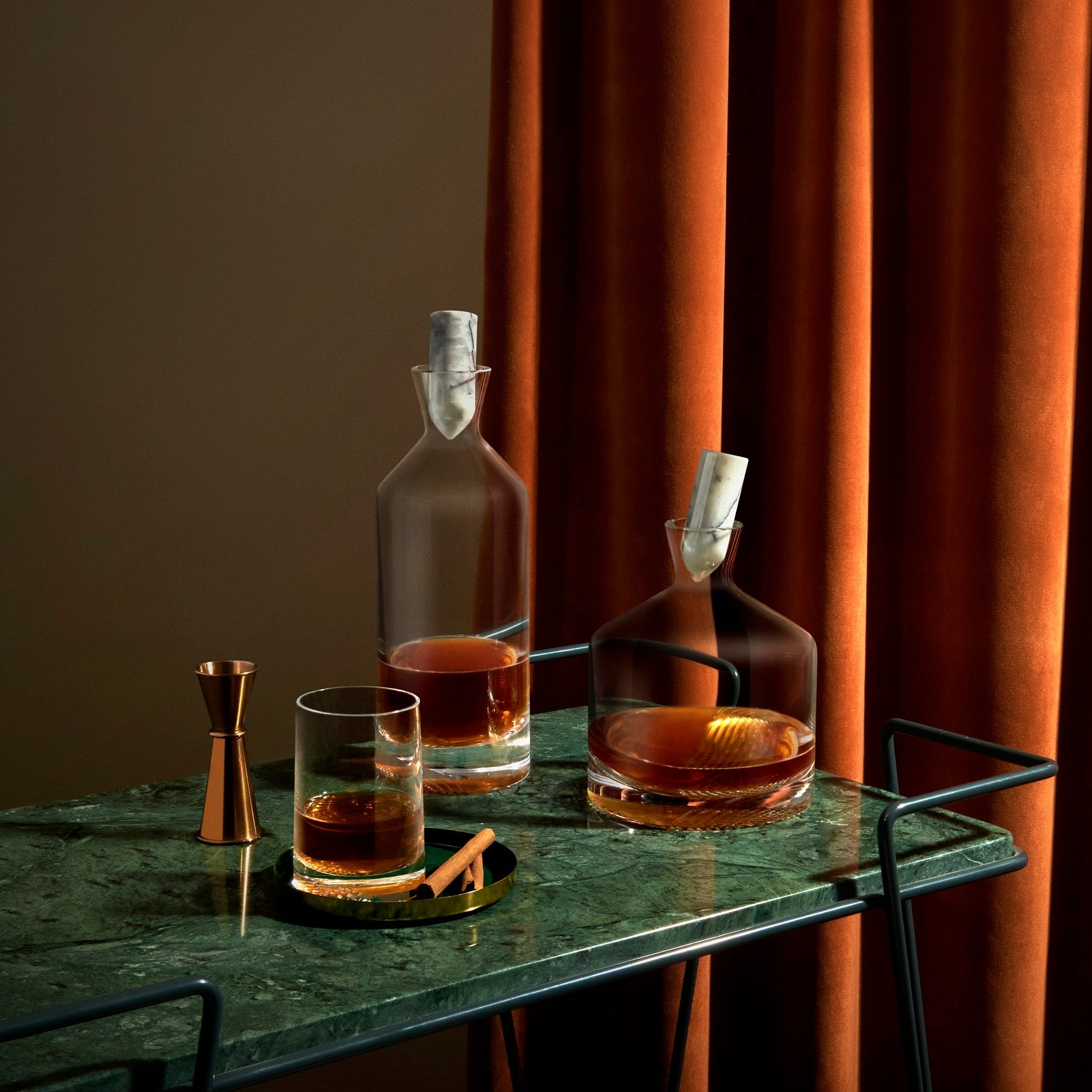 Elegant lifestyle display of two crystal whisky glasses and a crystal decanter with fine spirits.