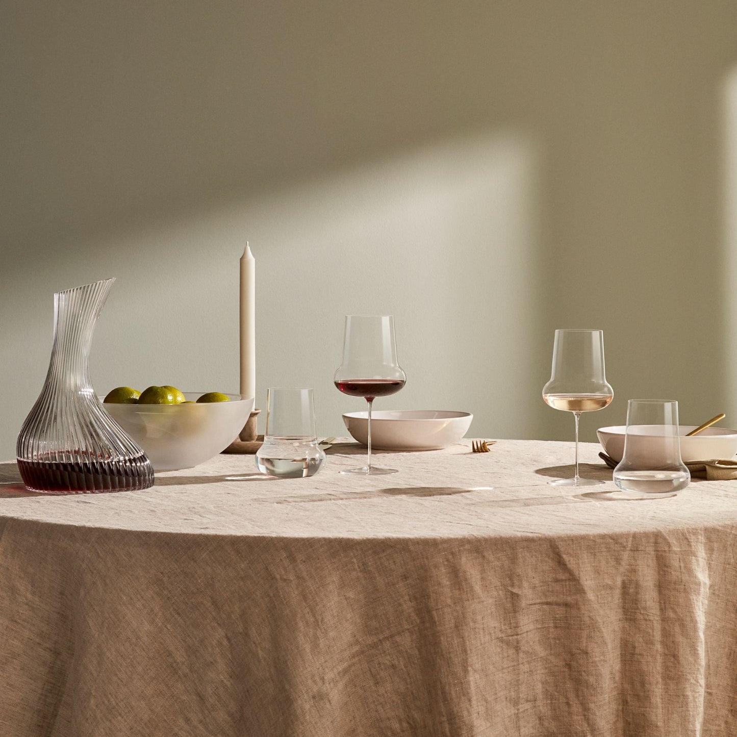 Two lightweight crystal tumblers placed on a contemporary dark wooden dining table.