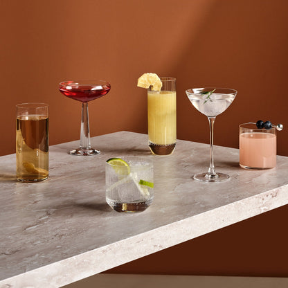 Two Finesse long drink glasses styled on a minimalist table with modern bar accessories.