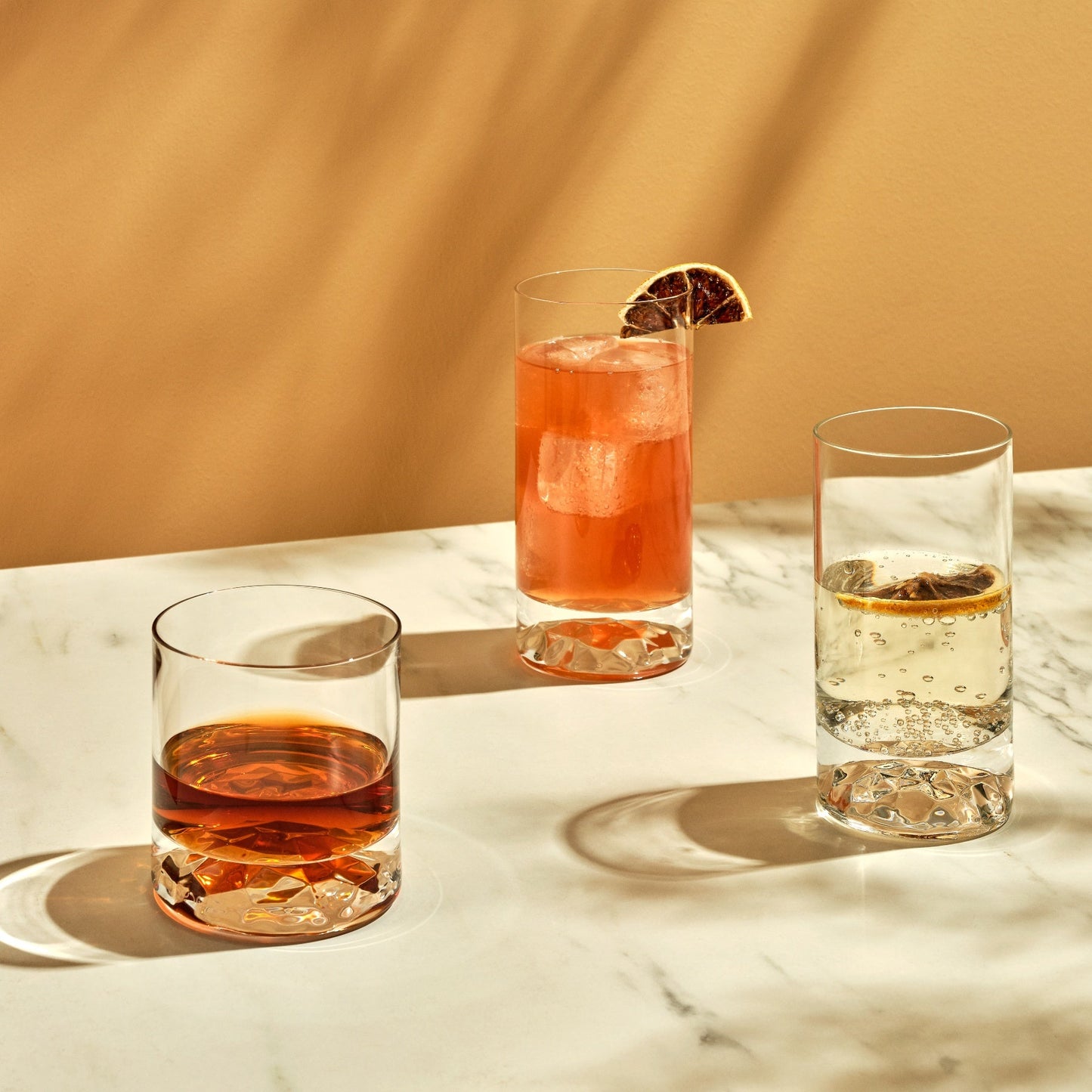 An elegant lifestyle setting featuring a modern crystal whisky glass on a wooden table.