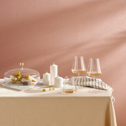 An elegant tabletop setting featuring NUDE Glass Stem Zero glassware filled with wine beside artisanal dishes.