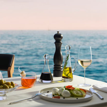 An elegant dining arrangement highlighting a modern oil bottle and the Stem Zero crystal glass.