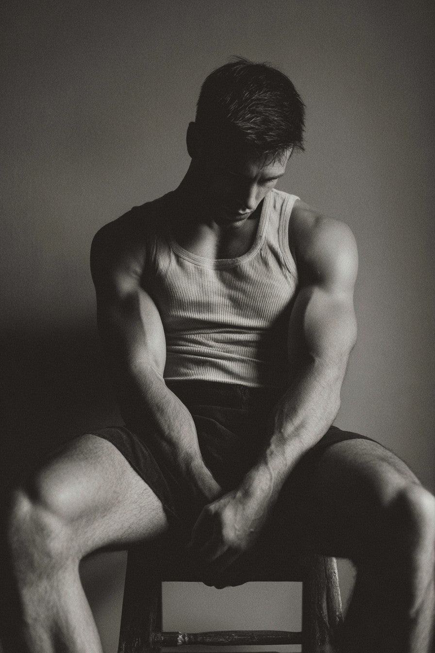 Fine art print of a seated man in sunlit denim, showcasing warm shadows and dramatic lighting.