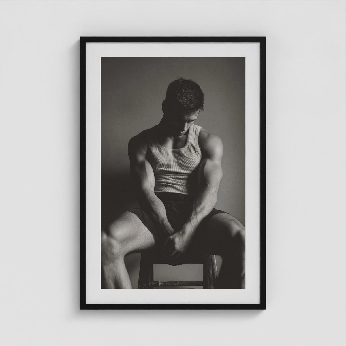 Seated male figure in denim portrait, framed in a twenty-four by thirty-six black box frame.
