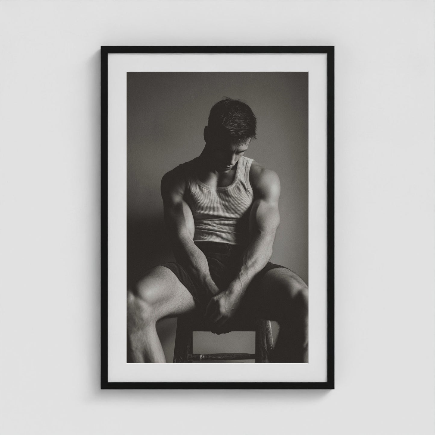 Seated male figure in denim portrait, framed in a twenty-four by thirty-six black box frame.