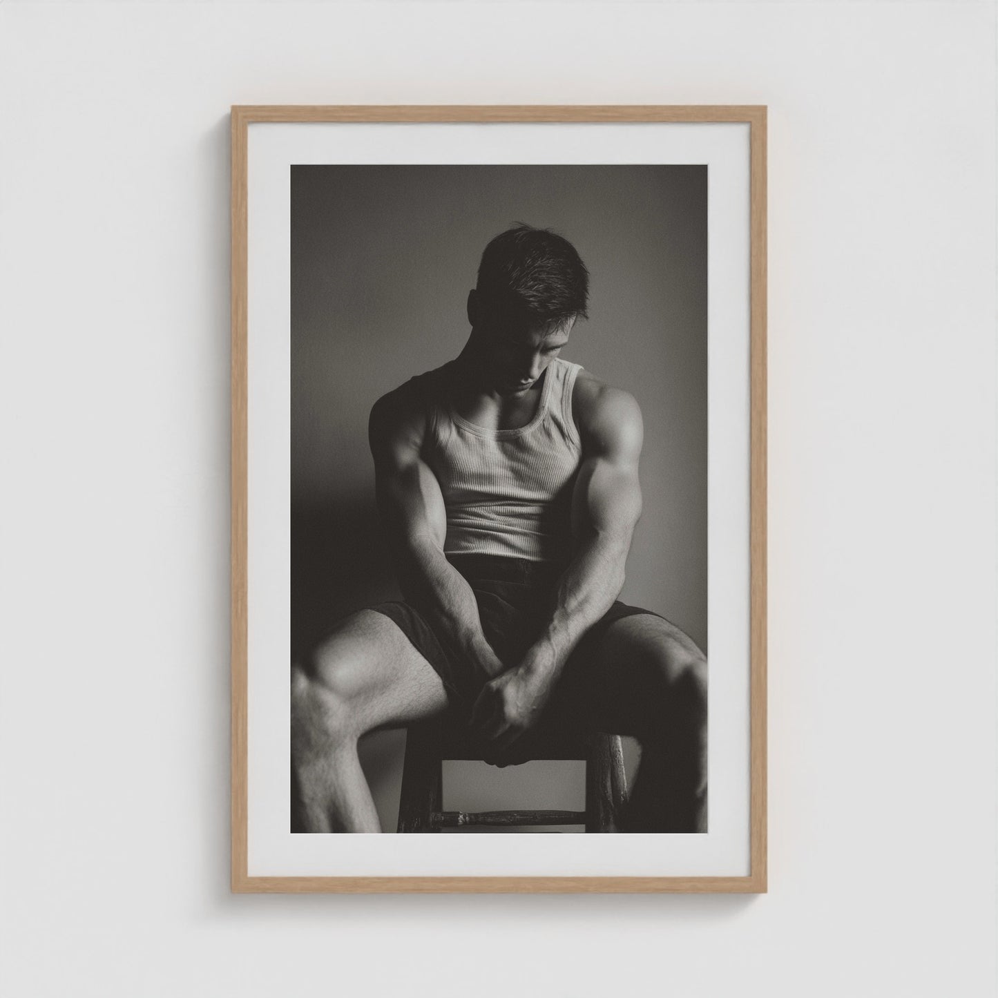 Seated male figure in denim portrait, framed in a twenty-four by thirty-six natural wood box frame.