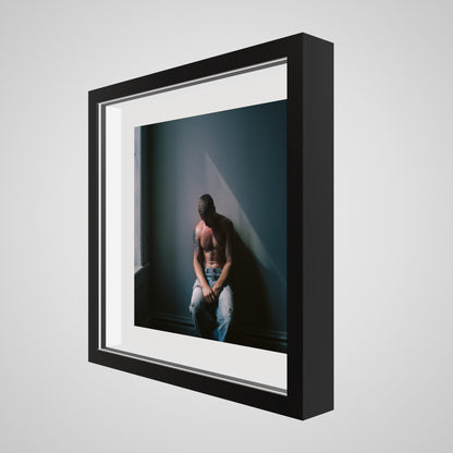Angled view of Contemplative Male Portrait Art Print in a 16x16 deep black square spacer frame