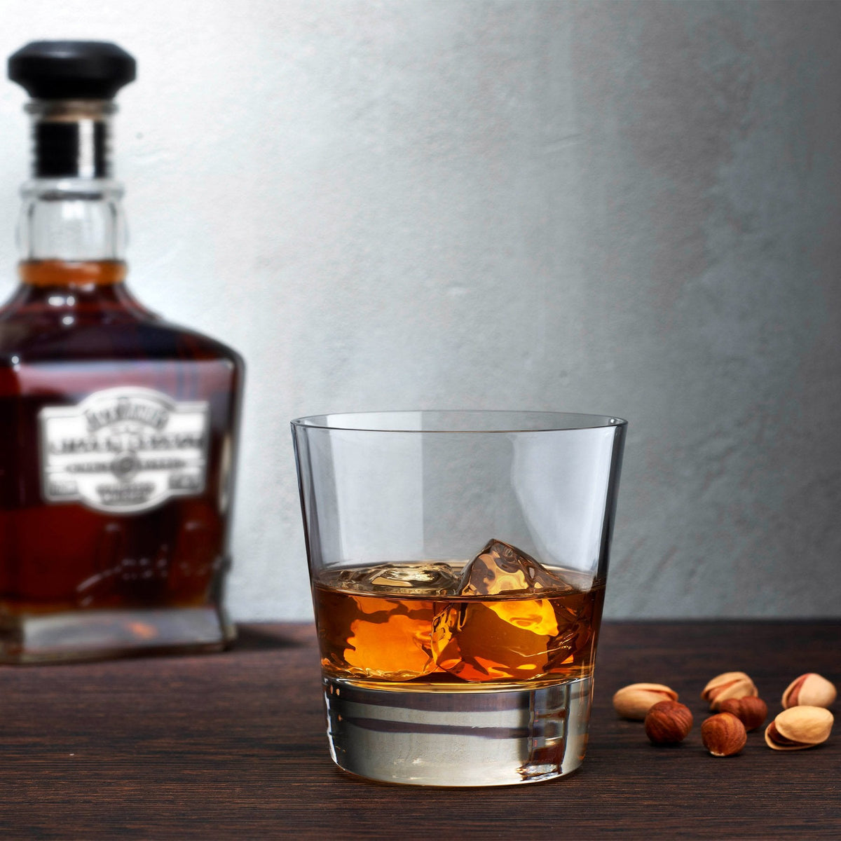 Lifestyle styling of the Highlands crystal whisky glasses on a modern wooden bar cart with a decanter.