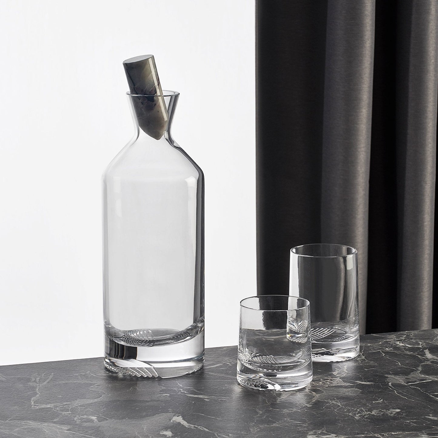 Curated barware set showcasing the Alba tall whisky bottle alongside companion crystal glasses on a dark surface.