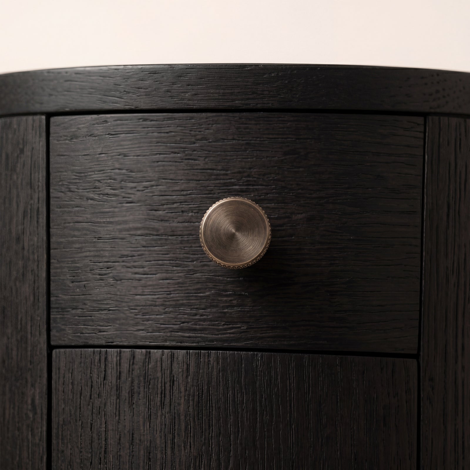 Close-up of the knurled brass pull hardware on the ebony ash wood door.