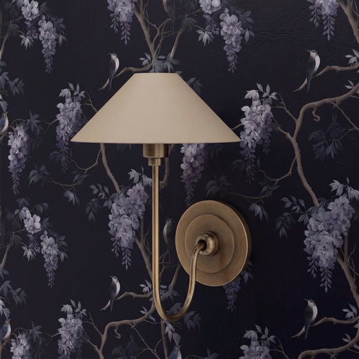 Detail of midnight blue botanical wallpaper featuring lilac wisteria blooms and swallows in a modern bedroom