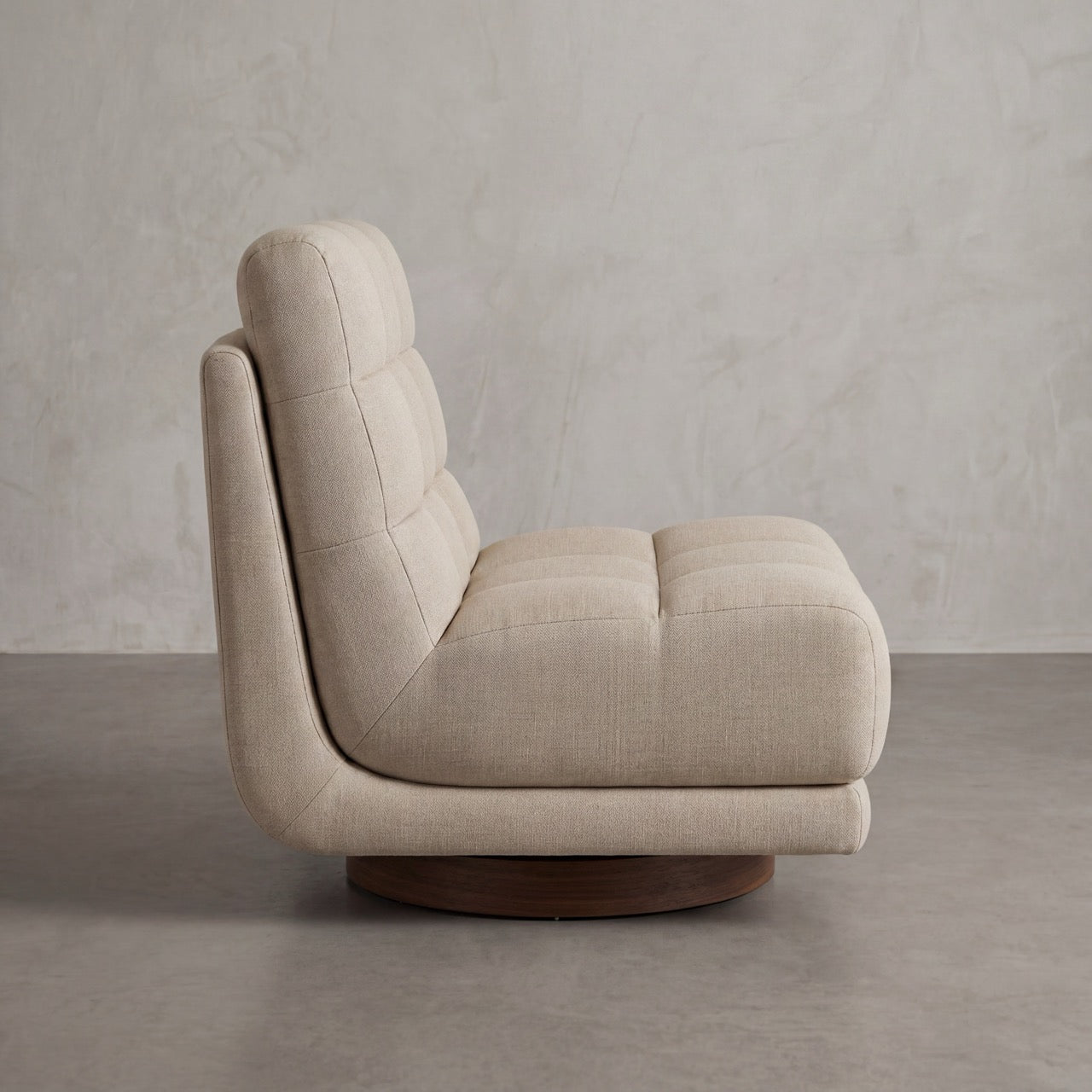 Angled view of the soft, generously cushioned Puffer swivel chair on its wood base.