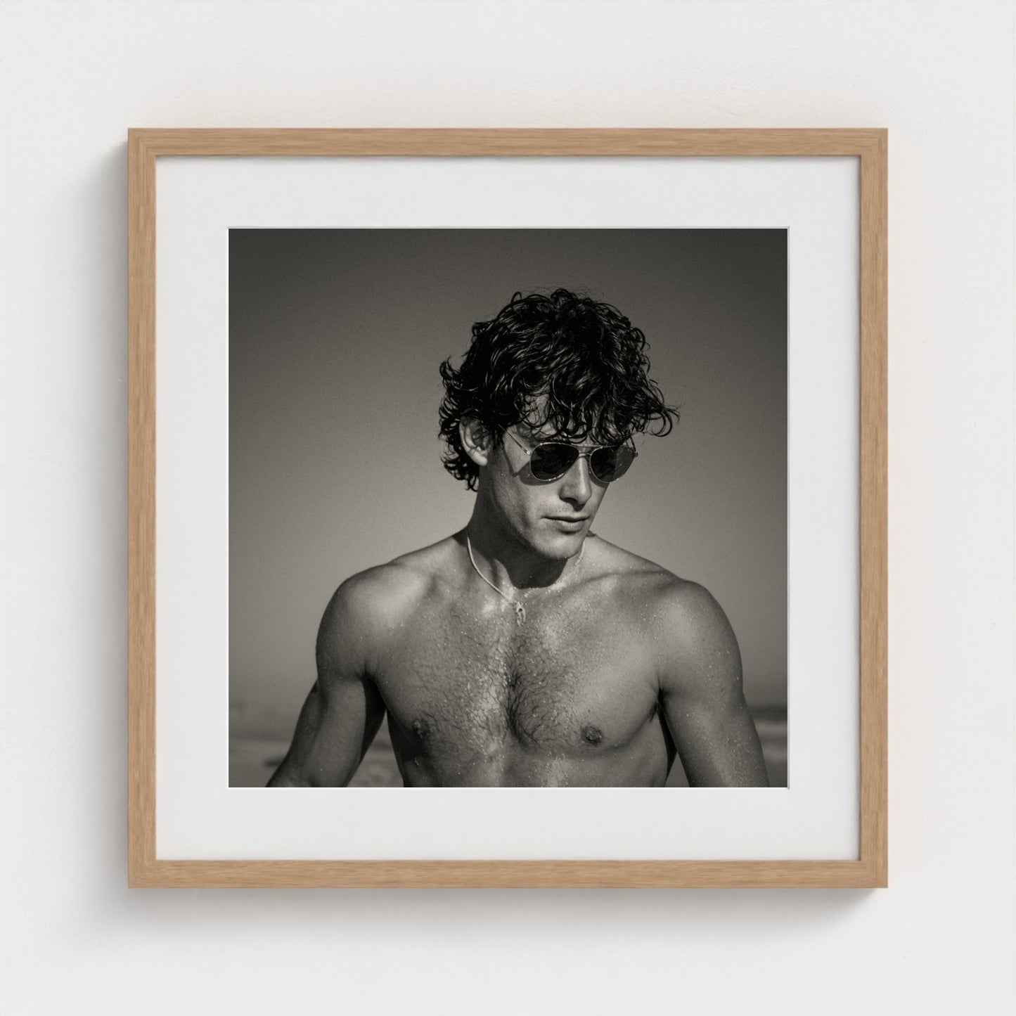 A 20x20 inch monochrome figure study art print set in a light natural wood frame.