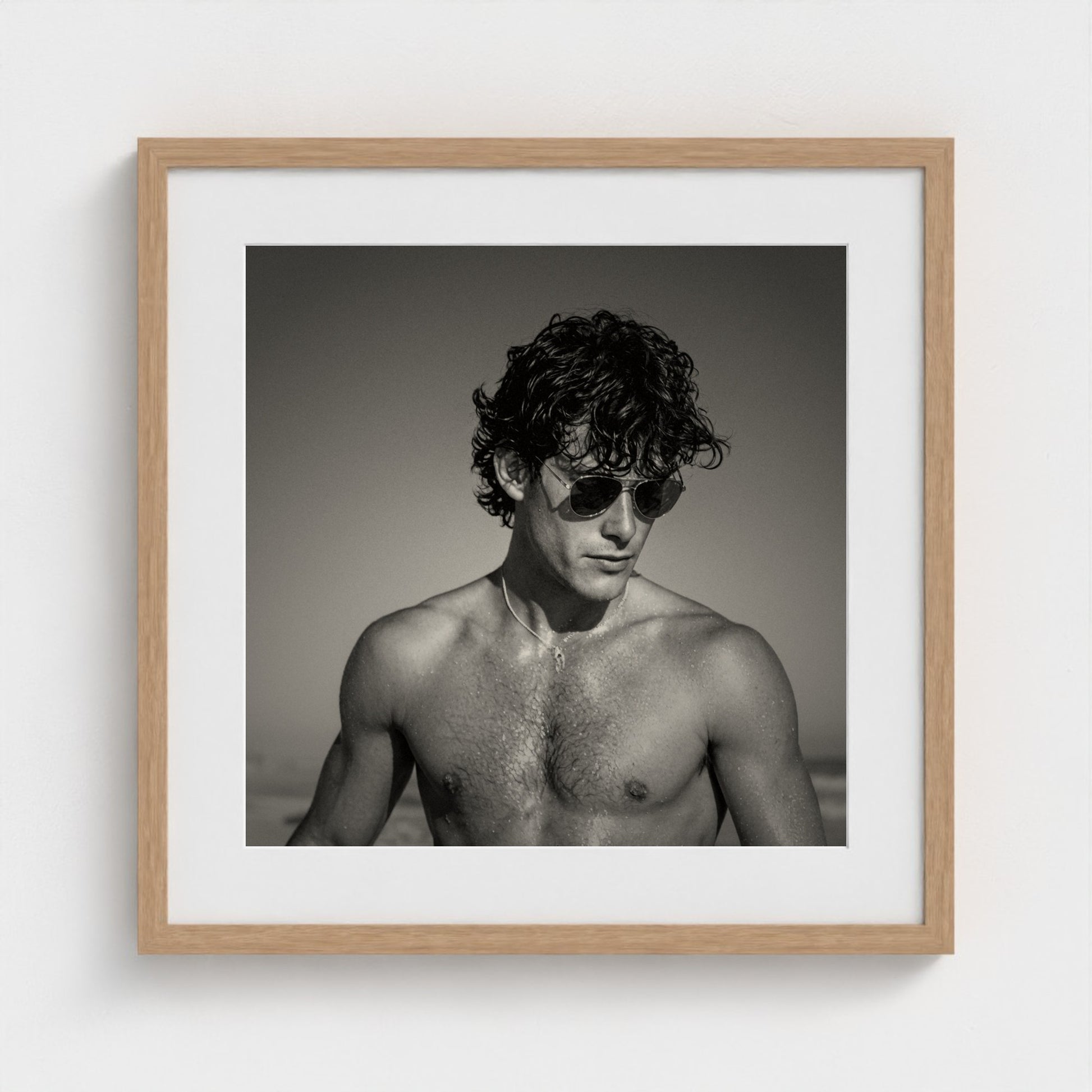 A 20x20 inch monochrome figure study art print set in a light natural wood frame.