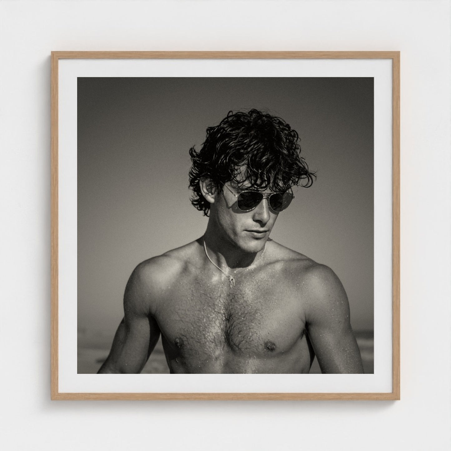 Monochrome fine art portrait in a 30x30 inch natural wood frame on a neutral wall.